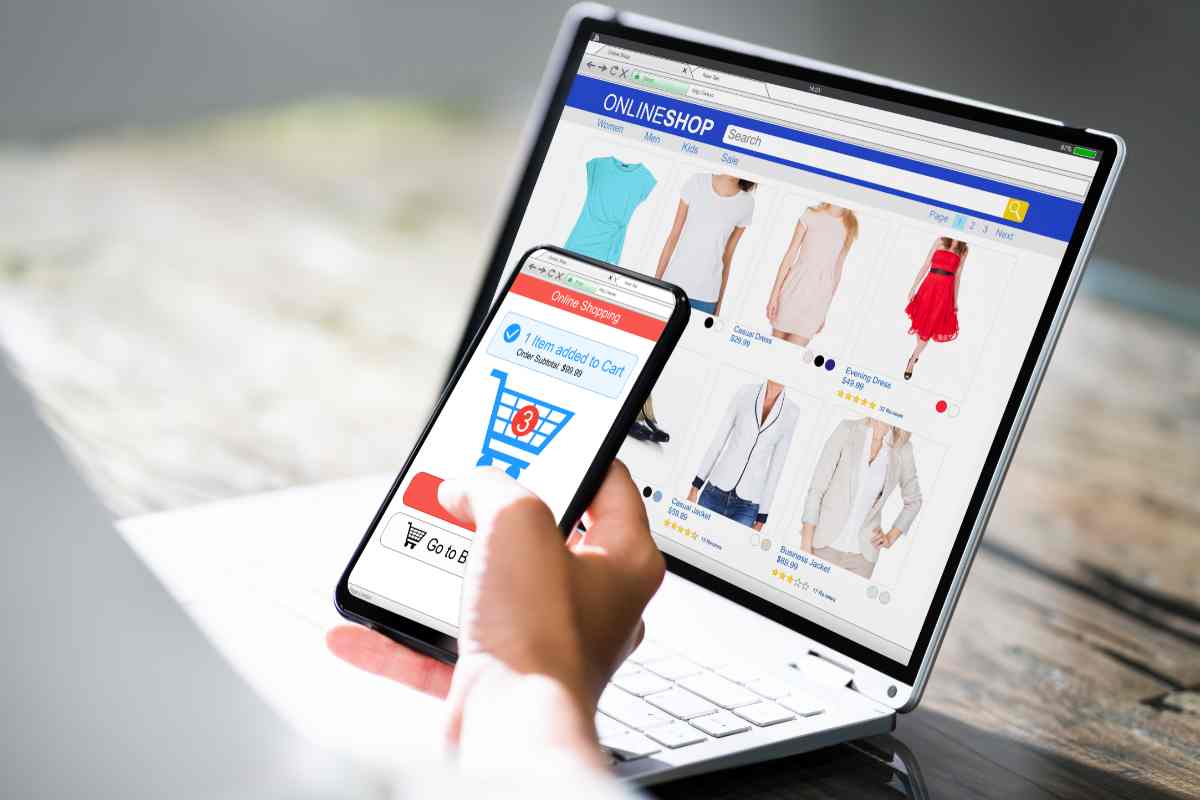 uomo davanti a pc con smartphone in mano